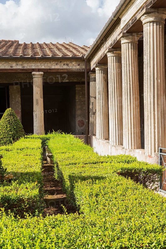 Large old building structure with columns and inner garden courtyard with a maze of trimmed hedges and topiary at the ancient ruins of Pompeii, Campania region, Italy, Europe