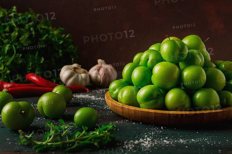 Tkemali, green cherry plum, with ingredients for sauce, cilantro, mint, hot pepper, garlic, on a wooden table, close-up, rustic, food background, no people, selective focus