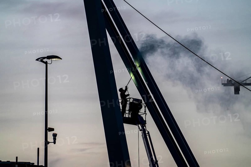 Worker cleans a bridge pier with a high-pressure cleaner on a cherry picker at the Erasmus Bridge over the Nieuwe Maas in Rotterdam, Netherlands