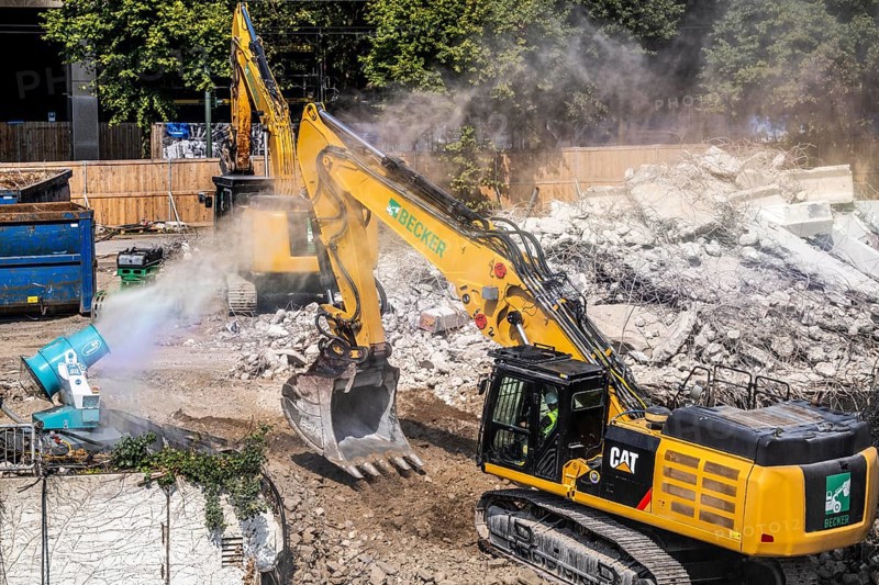 Water cannon, snow cannon, sprays water onto the construction site on Haroldstraße, against dust formation, demolition of a former office building, after complete gutting only the concrete parts remain, large excavator steel wire, Düsseldorf, North Rhine-Westphalia, Germany, Europe
