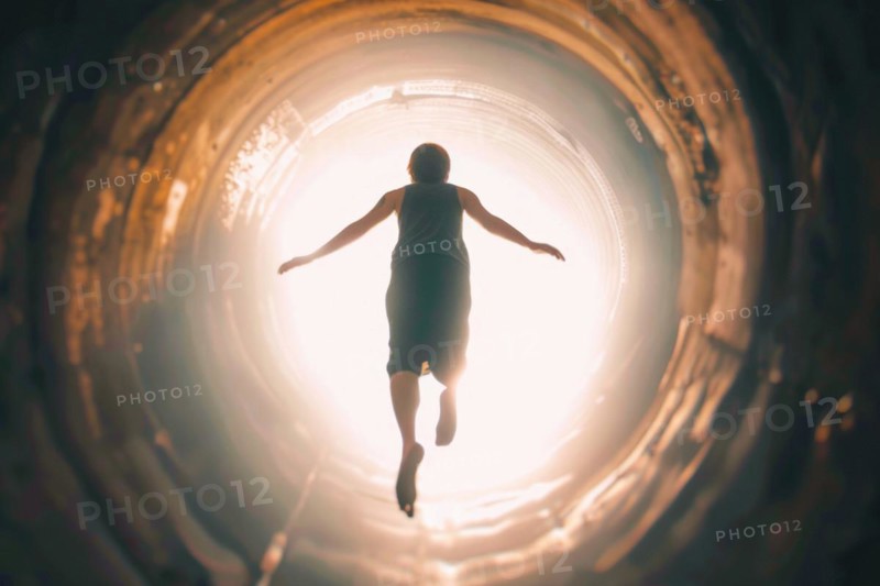 A young man floats through a tunnel into the light, symbolic image for near-death experience, death, grief, separation, idea of the afterlife, psychology, parapsychology, AI generated, AI generated, AI generated