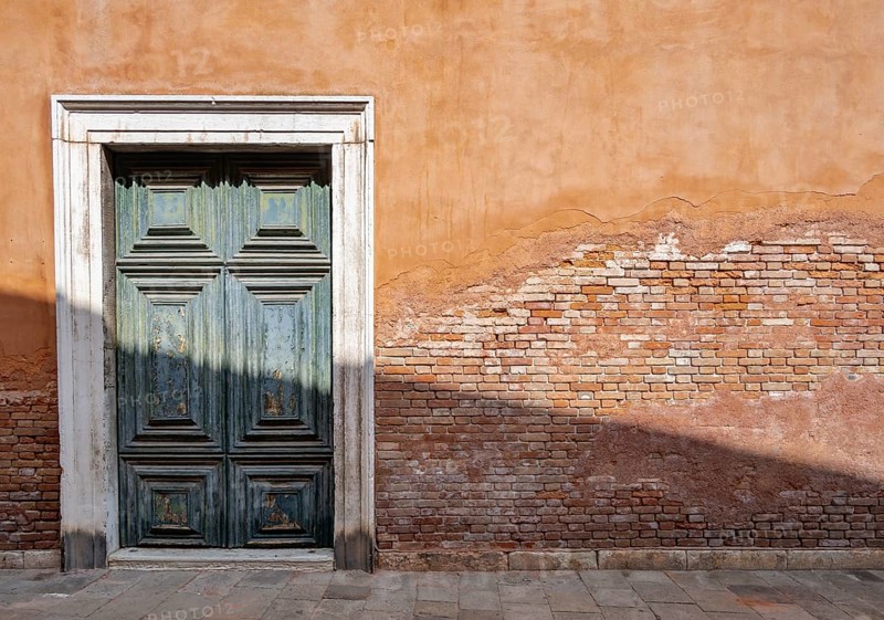 Red house facade with large green door, peeling plaster on brick wall, Venice, Veneto, Italy, Europe
