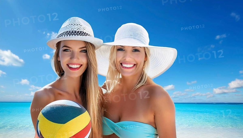 Two young woman in sun hats playing with a beach ball on the beach in the Caribbean