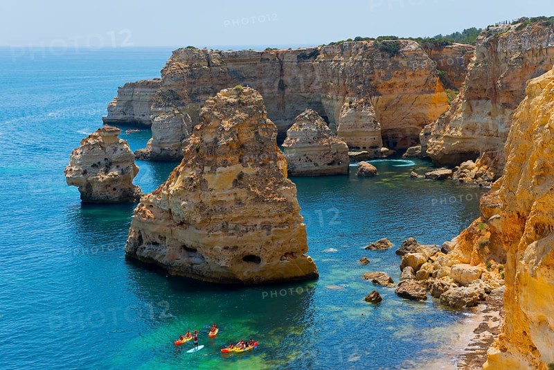 Several kayaks sail along imposing rocks rising from the clear blue sea, Praia da Marinha, Lagoa, Rocky Algarve, Algarve, Portugal, Europe