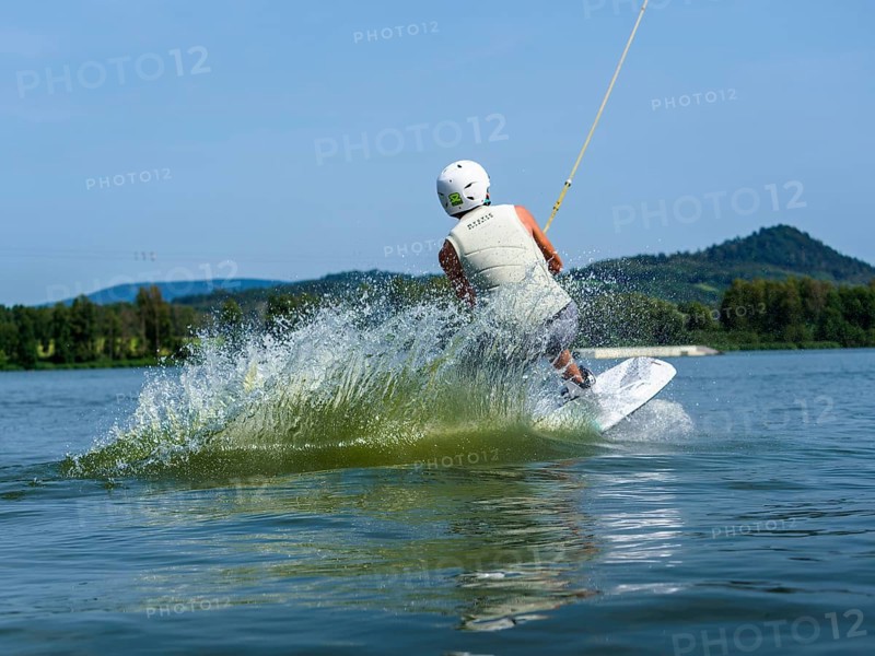 Young man jumping with wakeboard into the lake, water sports, water skiing in wakepark, Stráž pod Ralskem, Czech Republic, Europe