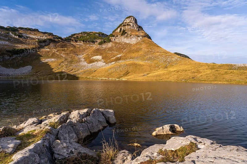 Lake Augstsee and the Atterkogel mountain on the Loser. Rocks in the foreground. Autumn, good weather, blue sky. Altaussee, Bad Aussee, Ausseer Land, Totes Gebirge, Styria, Upper Austria, Austria, Europe