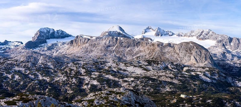 Panorama of the Dachstein mountains in autumn with some snow. From the left: Koppenkarstein, Schladminger Glacier, Hoher Gjaidstein, Hoher Dachstein, Niederer Dachstein, Steiner Scharte, Hallstätter Glacier, Taubenkogel, Hohes Kreuz. Blue sky with clouds. Dachstein massif, Upper Austria, Austria, Europe