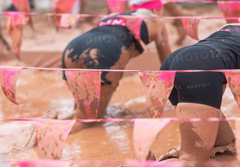 Participants in the mud during an athletic obstacle course
