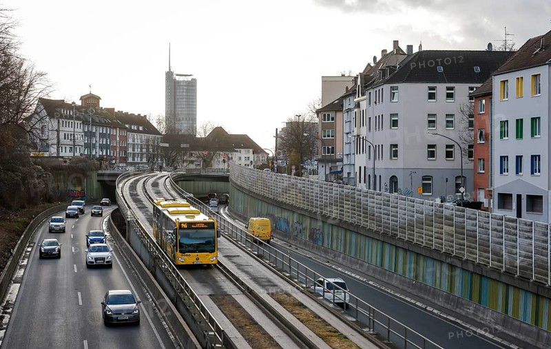 Essen, North Rhine-Westphalia, Germany - Cars and a public bus drive on the A40 motorway through the city centre of Essen, behind the Westenergie Tower, former RWE Tower