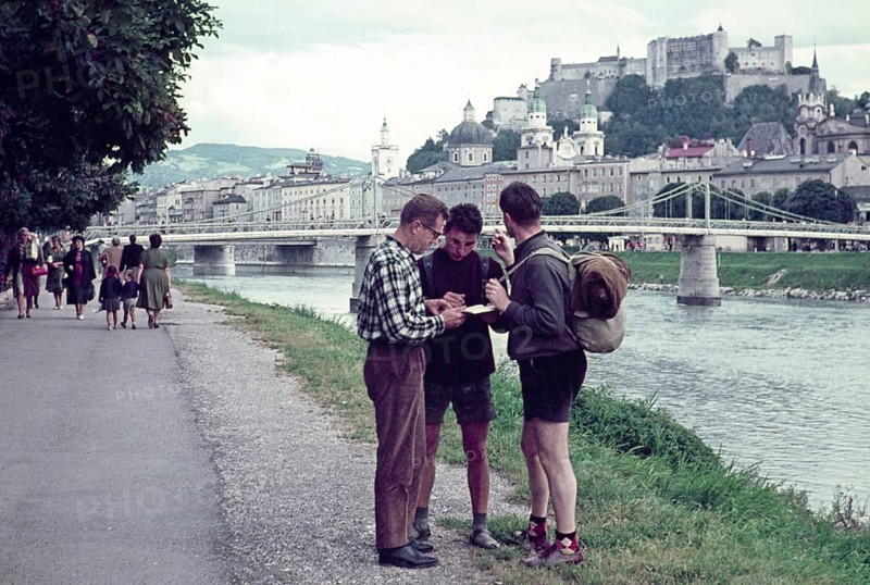 Two hitchhikers being helped with directions by a man, Salzach River riverbank, Salzburg, Austria early 1960s