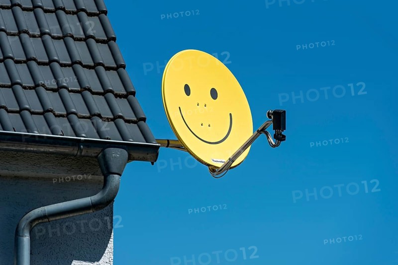 Funny satellite dish, yellow with smiley, satellite antenna on the roof of a house, satellite antenna, Hesse, Germany, Europe