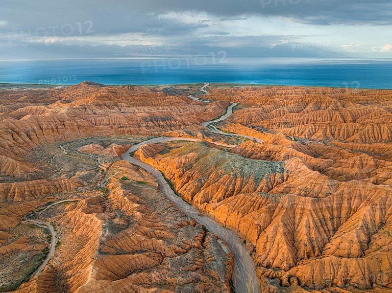 River bed runs through a landscape of eroded hills, badlands, Issyk Kul Lake in the background, aerial view, Canyon of the Forgotten Rivers, Issyk Kul, Kyrgyzstan, Asia