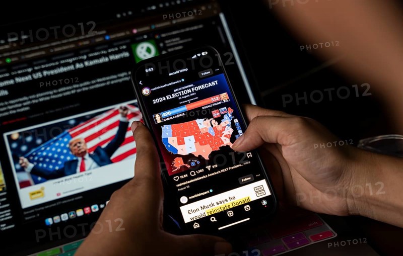 In this photo illustration, a person watch results of U.S. elections on a smartphone in Guwahati, India on 6 November 2024. Donald Trump has won the 2024 US presidential election and a second term in the White House, four years after losing the 2020