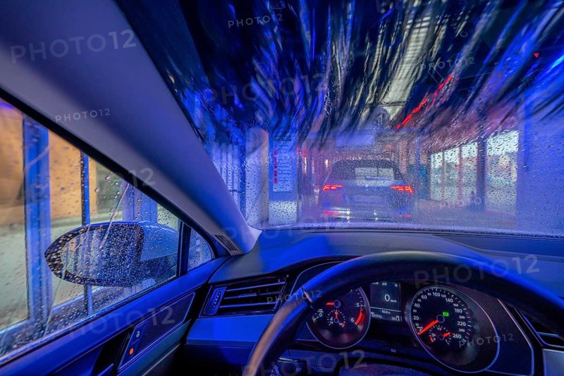 Car in an automatic car wash, car wash tunnel, cleaning foam is sprayed on, rotating brushes clean the vehicle