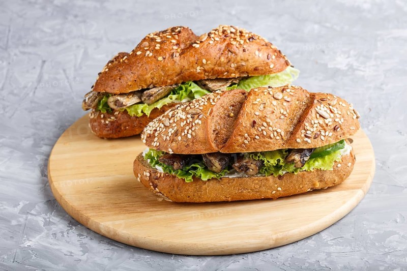 Sprats sandwiches with lettuce and cream cheese on wooden board on a gray concrete background. side view, close up