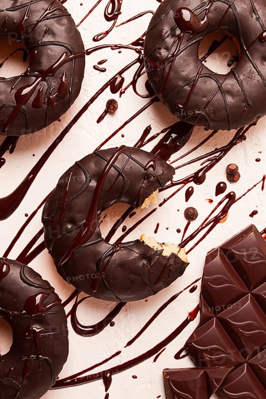Donuts, in chocolate glaze, on a beige background, with liquid chocolate