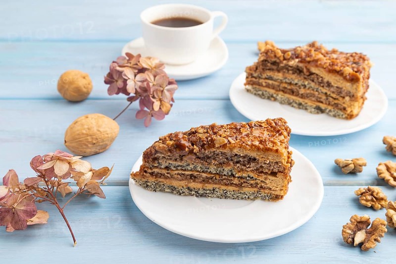 Walnut and hazelnut cake with caramel cream, cup of coffee on blue wooden background. side view, copy space