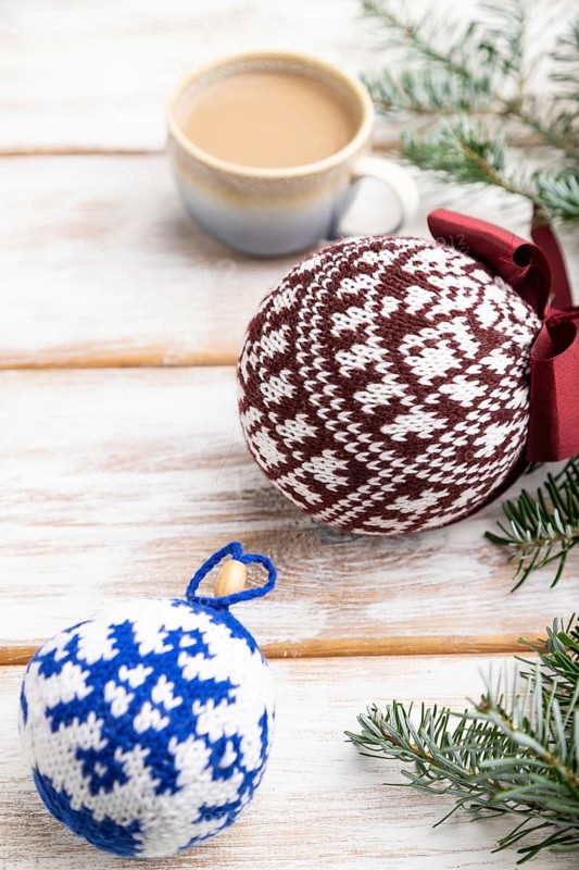 Christmas or New Year composition. Decorations, knitted balls, fir and spruce branches, cup of coffee, on a white wooden background. Side view, close up, selective focus