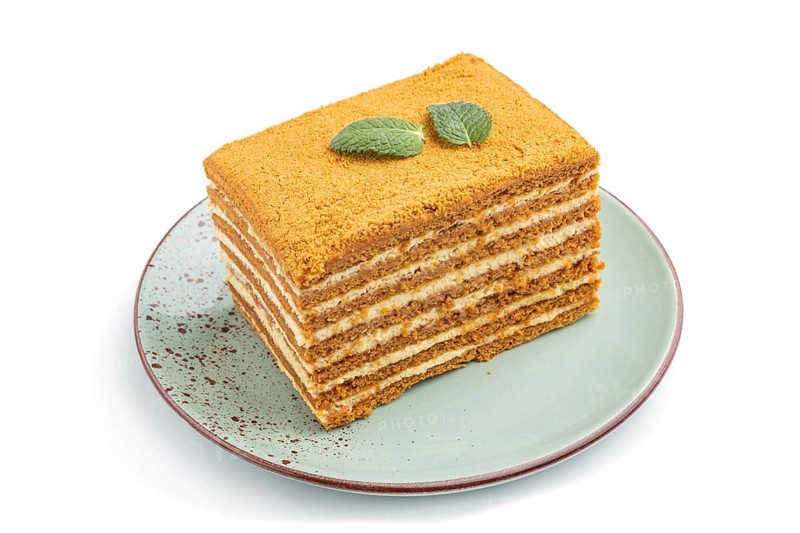 Homemade honey cake with milk cream and mint isolated on white background. Side view, close up