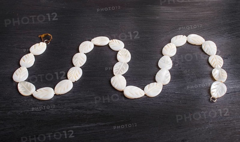 White nacre leaves beads on a black background. top view, close up