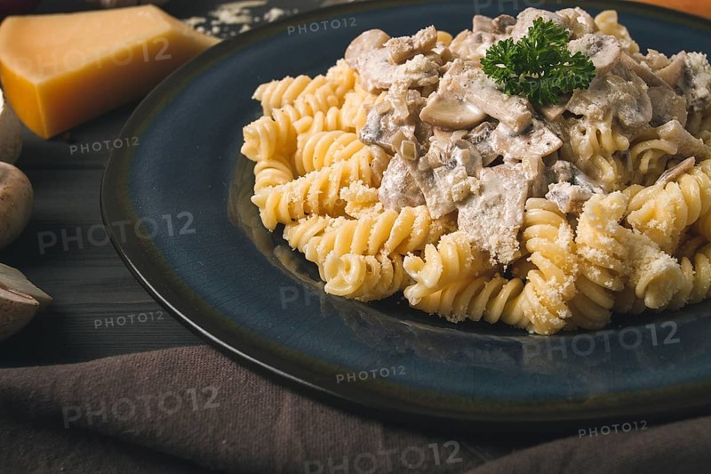 Fusilli pasta, with champignons in cream sauce, top view, with ingredients, on a wooden table, no people