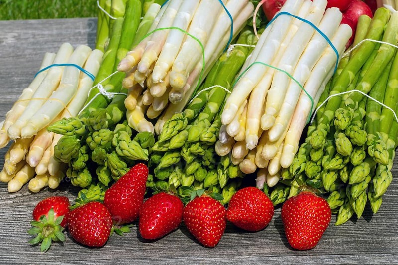 Green asparagus, white asparagus and fresh strawberries decorated on a rustic wooden table