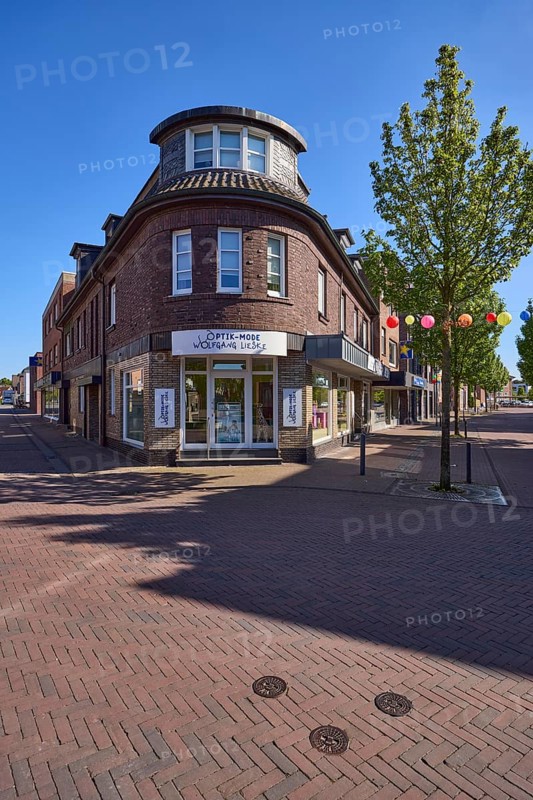 Brick corner building with optician's shop at the junction of Bahnhofstraße and Wehrstraße in Rhede, Münsterland, Borken district, North Rhine-Westphalia, Germany, Europe