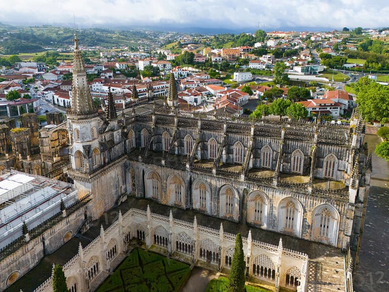 Aerial view of a Gothic cathedral with a tower and detailed windows, embedded in an urban landscape and surrounded by green nature, aerial view, monastery, Mosteiro de Santa Maria da Vitória, 'unfinished chapels', UNESCO World Heritage Site, Batalha, Leiria, Estremadura, Portugal, Europe