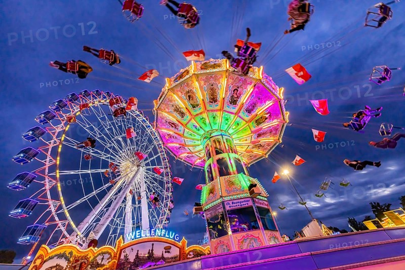 Chain carousel and Ferris wheel in the evening. 177th Cannstatter Volksfest at the Cannstatter Wasen. Bad Cannstatt, Stuttgart, Baden-Württemberg, Germany, Europe