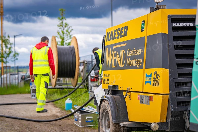 A construction worker works on a construction site with a large cable drum and machines outdoors, fibre optic installation, Calw district, Black Forest, Germany, Europe