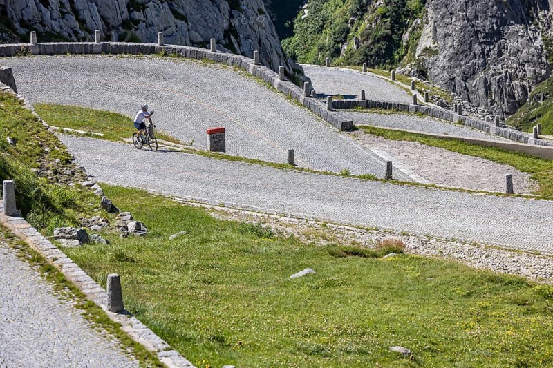 Cyclists on the road on La Tremola, the world-famous Alpine pass through the Val Tremolo, Switzerland's longest road construction monument with 24 hairpin bends. Airolo, Canton Ticino, Switzerland, Europe