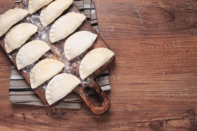 Traditional Polish dish, dumplings, raw, frozen, on a cutting board, wooden table, top view, no people