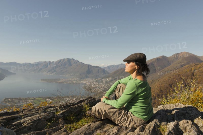 Woman with Flat Cap Sitting and Enjoy Panoramic View Over Mountain and Alpine Lake Maggiore in Ticino, Switzerland, Europe