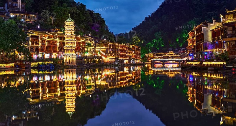 Chinese tourist attraction destination, Feng Huang Ancient Town (Phoenix Ancient Town) on Tuo Jiang River illuminated at night. Hunan Province, China, Asia