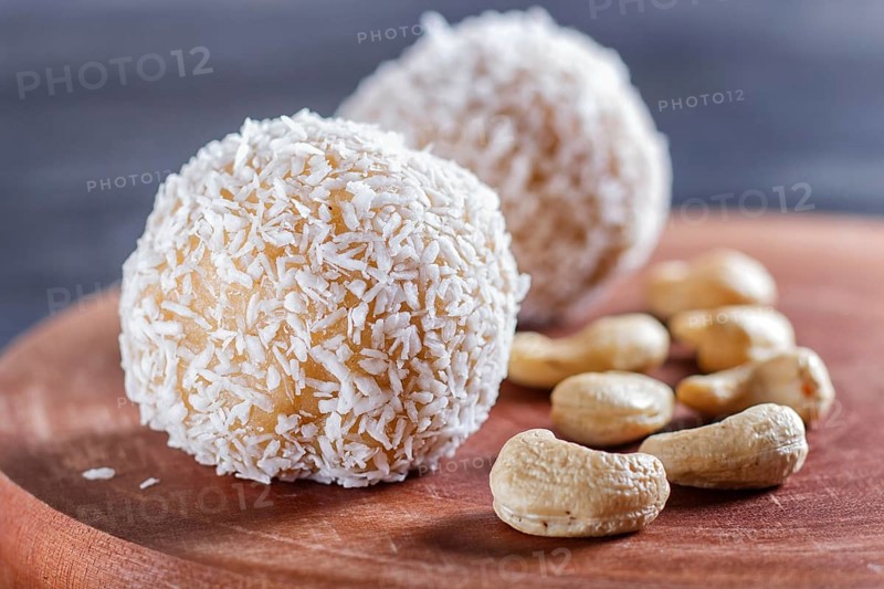 Energy balls cakes with coconut and cashew on wooden board on black background. selective focus, close up