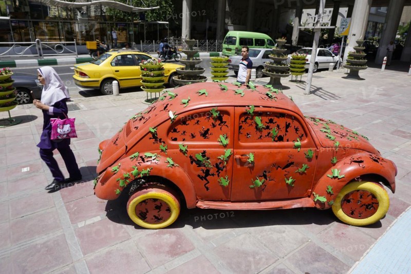 A woman walks past a Volkswagen Beetle art object on the pavement in Tehran. The city of Tehran is changing the image of the city through art objects in public spaces, 17.05.2016