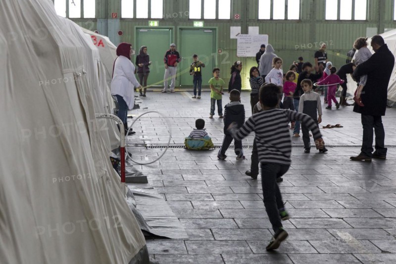 Children of refugees playing between tents in an emergency shelter for refugees on 9 December 2015 in the former hangar of Tempelhof Airport, Berlin, Berlin, Germany, Europe