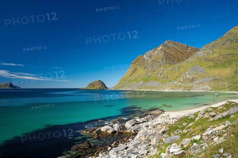 Landscape with sea at Haukland beach. On the right the mountains Veggen and Mannen. Shot during the day with blue sky. Early summer. Haukland Beach, Haukland, Vestvagoya, Lofoten, Norway, Europe