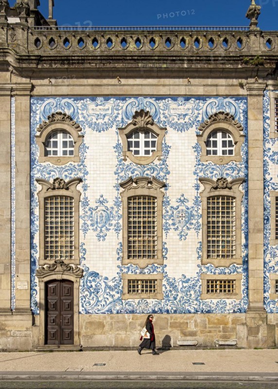 Woman passes by the facade of Igreja do Carmo church, adorned with intricate blue and white tiles, Porto, Portugal, Europe