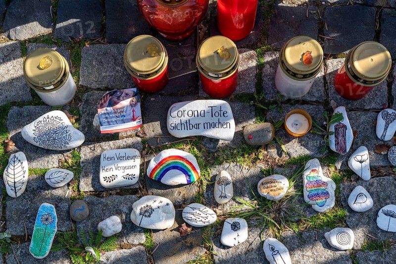 Candles and stones with inscriptions in memory of the dead of the corona pandemic, stickers from anti-vaccination campaigners, market square in the old town centre of Düsseldorf, North Rhine-Westphalia, Germany, Europe