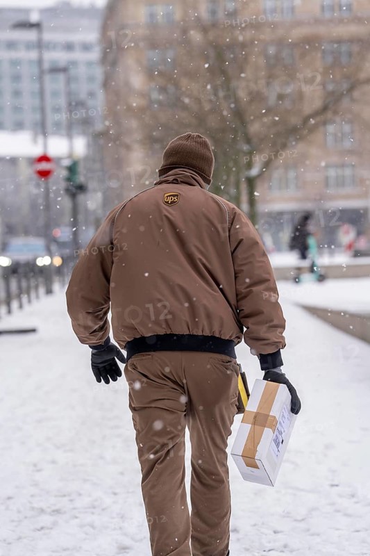 Winter in Frankfurt, UPS employee brings a parcel to a customer, on foot, because of the winter weather in the banking district, Hesse, Germany, Europe
