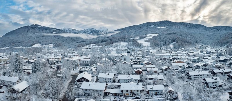 Snow-covered village in a mountain landscape under a cloudy sky, Bad Feilnbach