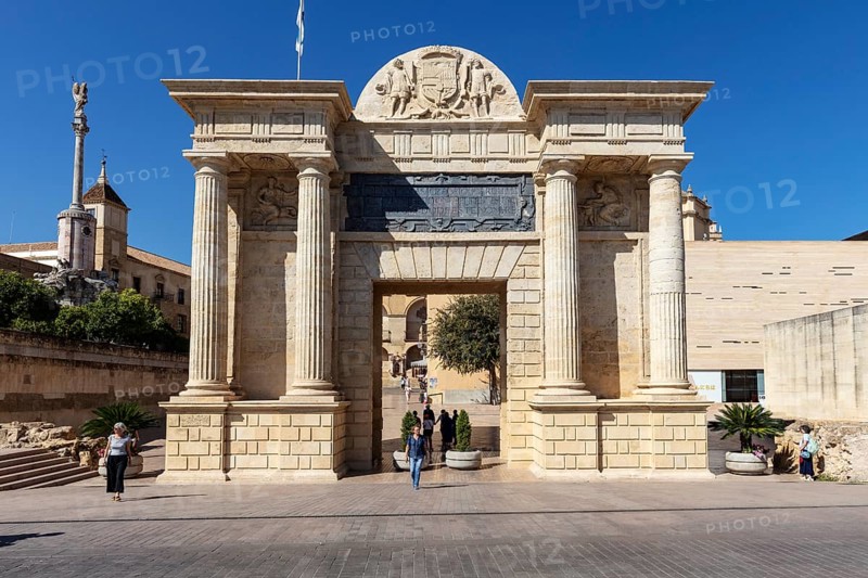 A monumental entrance with reliefs and columns under a blue sky, Cordoba