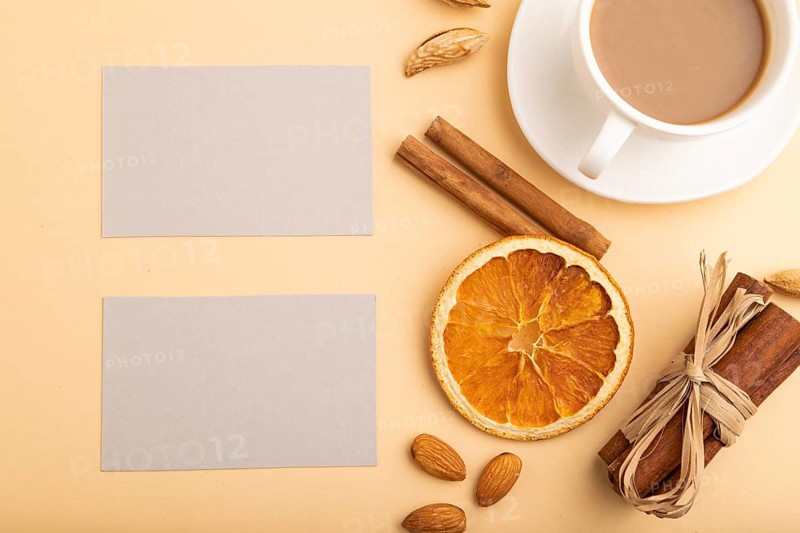 Composition of gray paper business cards, almonds, cinnamon and cup of coffee. mockup on orange background. Blank, top view, still life, flat lay, copy space