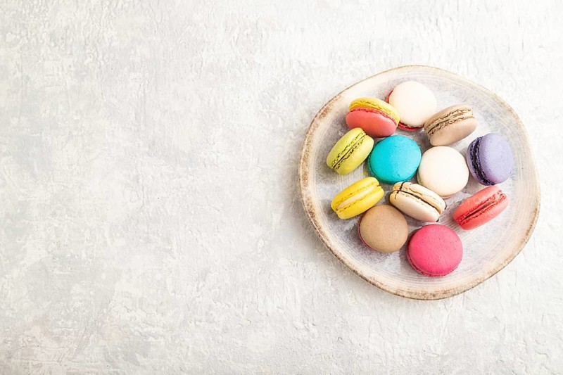 Multicolored macaroons on ceramic plate on gray concrete background. top view, copy space, still life. Breakfast, morning, concept
