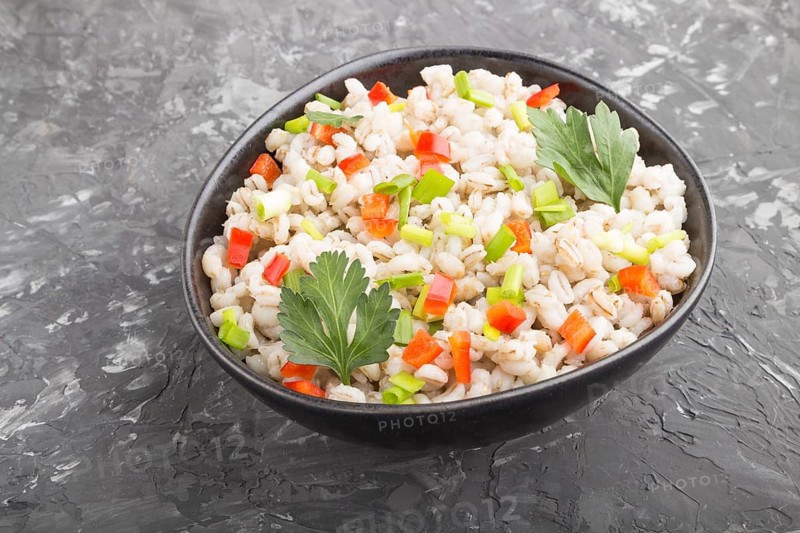 Pearl barley porridge with vegetables in blue ceramic bowl on a black concrete background. side view, close up. Russian traditional cuisine