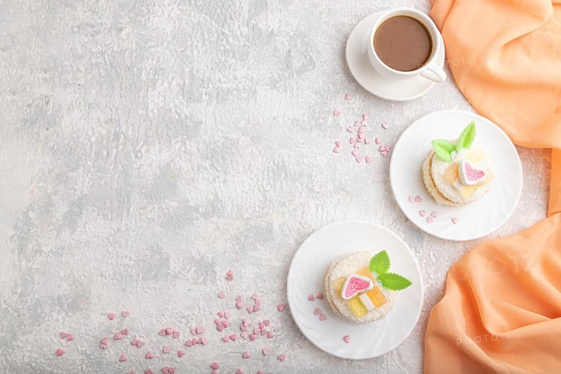 Decorated cake with milk and coconut cream with cup of coffee on a gray concrete background and orange textile. top view, flat lay, copy space