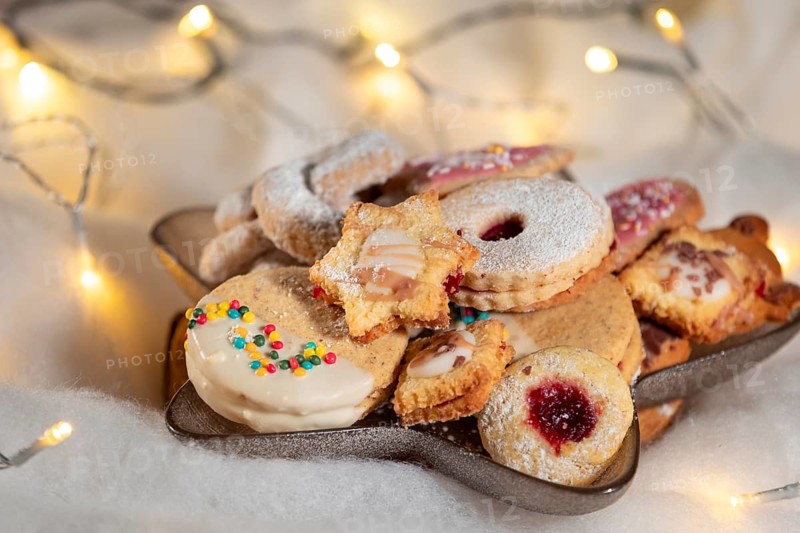 A plate full of Christmas biscuits with colourful sprinkles and soft lighting
