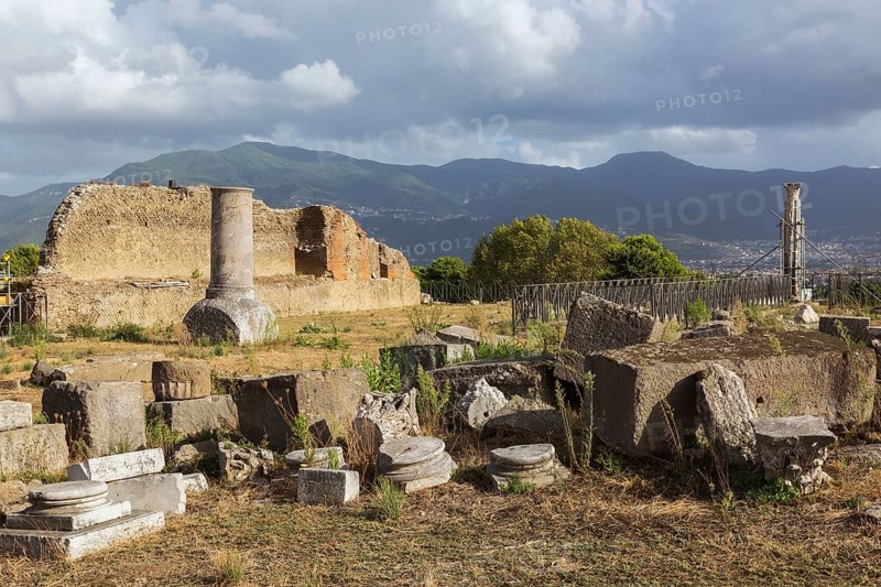 Old broken pieces of marble columns and slabs of carved stone plus remnant of terracotta brick and stone wall structure at the ancient ruins of Pompeii, Campania region, Italy, Europe