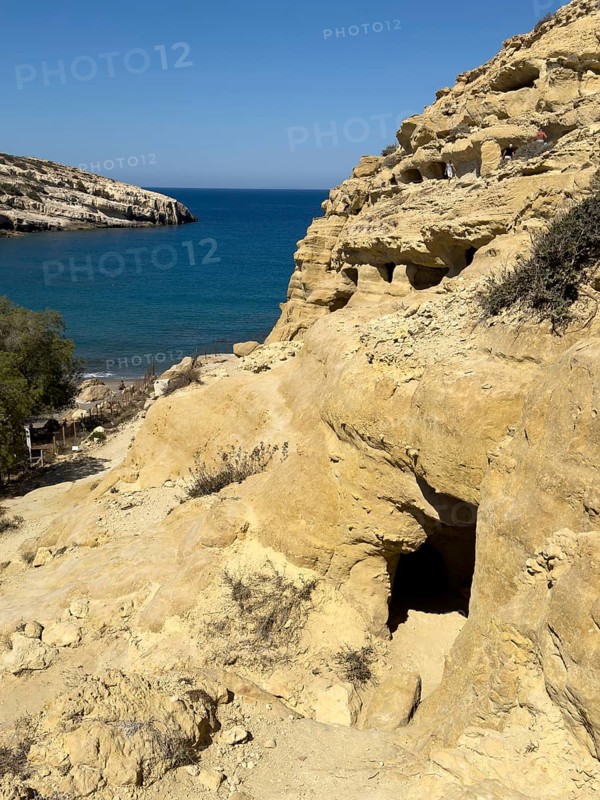 View of entrances of caves in sandstone rocks of former Roman necropolis with sandstone caves carved into sandstone Cave tombs Grottoes in rocks on the north side of Matala Bay, in the 60s and 70s hippie caves Caves for dropouts and hippies today excursion destination on the south coast of Crete island, left at the edge of the picture Libyan Sea Mediterranean, Matala, Crete, Greece, Europe